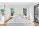 Bright main bedroom with large windows, blonde wood floors, a platform bed and ensuite bath at 2177 Sunnyside Pl, Sarasota, FL 34239