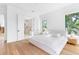 Bright bedroom with blonde wood flooring and ensuite bath featuring double doors, white walls and a large window at 2177 Sunnyside Pl, Sarasota, FL 34239