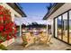 Outdoor patio with four chairs, pool and lush landscaping at sunset at 2177 Sunnyside Pl, Sarasota, FL 34239