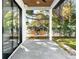 This covered porch features a wooden swing, ceiling fan, and a view of the serene backyard at 2177 Sunnyside Pl, Sarasota, FL 34239