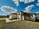 Close-up of a one-story stucco home featuring a two-car garage and arched entrance with palm trees in the front yard at 26313 84Th E Ave, Myakka City, FL 34251