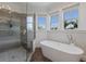 Beautiful bathroom featuring a glass-enclosed shower and a soaking tub under a bright window at 3916 N Shell Rd, Sarasota, FL 34242