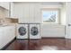 Bright laundry room with wooden floors, front loading washer/dryer, and built-in storage at 4129 Roberts Point Cir, Sarasota, FL 34242