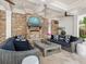 Cozy outdoor living space with a stone fireplace, comfortable seating, and a modern chandelier at 4129 Roberts Point Cir, Sarasota, FL 34242