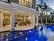 Inviting pool with covered patio featuring stone fireplace, comfortable seating, and stylish chandelier at 4129 Roberts Point Cir, Sarasota, FL 34242