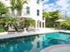 A luxurious pool surrounded by a white patio and lush greenery offers a serene backyard retreat at 4129 Roberts Point Cir, Sarasota, FL 34242