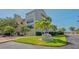 Exterior of building with well-manicured lawn, palm trees, and signage for 