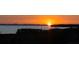 Silhouette of land and trees are visible in front of a vibrant sunset over the water at 4535 Bay Club Dr, Bradenton, FL 34210