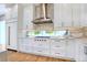 Well-appointed kitchen featuring white cabinetry, stone backsplash, stainless steel hood, and high-end appliances at 5103 Windward Ave, Sarasota, FL 34242