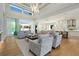 Open-concept living room with light wood floors, plush seating, high ceilings, and seamless flow to outdoor spaces at 5103 Windward Ave, Sarasota, FL 34242