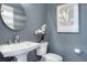 Stylish powder room boasts a pedestal sink, round mirror, and elegant wall covering at 5103 Windward Ave, Sarasota, FL 34242