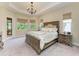 Beautiful bedroom with tray ceilings, chandelier, lots of light from the many windows, and a door to the outside at 515 Honeyflower Loop, Bradenton, FL 34212