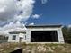 Garage opening on a one-story unfinished home with a metal roof shown under a cloudy, bright, blue sky at 6970 Beckwith Ave, North Port, FL 34291