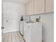 Bright laundry room with white appliances, overhead cabinets, and tiled flooring at 7402 8Th W Ave, Bradenton, FL 34209