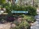 A picturesque community sign 'Pine Bay Forest' is surrounded by lush, green landscaping and pine needles at 7523 4Th W Ave # 7523, Bradenton, FL 34209