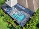 Aerial view of a sparkling pool inside a screened enclosure, a patio with seating, and lush, mature landscaping at 813 Tailwind Pl, Sarasota, FL 34240