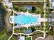 Aerial view showcases a rectangular community pool lined with lounge chairs and lush tropical landscaping at 813 Tailwind Pl, Sarasota, FL 34240