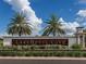 The entrance to the Lakehouse Cove community with manicured landscaping and a blue sky background at 813 Tailwind Pl, Sarasota, FL 34240