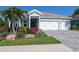 Charming single-Gathering home featuring a three-car garage and beautifully landscaped front yard with flowering plants at 813 Tailwind Pl, Sarasota, FL 34240