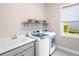 Bright laundry room with washer, dryer, sink, and shelving for storage and organization at 813 Tailwind Pl, Sarasota, FL 34240