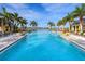 Expansive community pool with clear blue water, palm trees and comfortable lounge chairs at 813 Tailwind Pl, Sarasota, FL 34240
