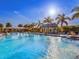 Expansive community pool with fountains, palm trees and lounge chairs under a bright blue sky at 813 Tailwind Pl, Sarasota, FL 34240