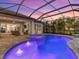 Beautifully lit in-ground pool and spa on a brick patio with palm trees, with patio seating under the covered lanai at 813 Tailwind Pl, Sarasota, FL 34240