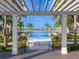 Inviting community pool framed by a pergola, palm trees, and lush landscaping with lake views at 813 Tailwind Pl, Sarasota, FL 34240