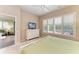 Comfortable bedroom featuring plantation shutters, white dresser with TV and a view to an adjacent living space at 8782 49Th E Ter, Bradenton, FL 34211