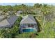 An aerial view shows a screened-in pool surrounded by lush greenery and a gray tiled roof in a quiet neighborhood at 8782 49Th E Ter, Bradenton, FL 34211