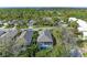 An aerial view shows a screened-in pool surrounded by lush greenery and a gray tiled roof in a quiet neighborhood at 8782 49Th E Ter, Bradenton, FL 34211