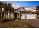 Charming single-story home featuring a spacious three-car garage, palm trees, and beautiful sunset sky at 922 Fernleaf Run, Bradenton, FL 34212