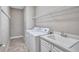 Laundry room with washer, dryer, utility sink, white wire rack, and tile floor at 110 167Th E Blvd, Bradenton, FL 34212