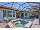 Inviting screened-in pool area features a spa, lounge chairs, and views of the home's expansive backyard at 110 167Th E Blvd, Bradenton, FL 34212