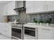 Modern kitchen with sleek white cabinets, stainless steel appliances, and a stylish blue and silver mosaic tile backsplash at 111 S Pineapple Ave # 918, Sarasota, FL 34236
