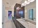 Modern bathroom with double sinks, granite countertops, and ample dark wood cabinet storage at 11408 Drifting Leaf Dr, Riverview, FL 33579