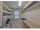 Well-lit laundry room equipped with modern washer, dryer, ample shelving, and a stylish countertop at 11408 Drifting Leaf Dr, Riverview, FL 33579