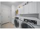 Functional laundry room with a washer and dryer, white cabinets, and tiled flooring at 12225 Whisper Lake Dr, Bradenton, FL 34211