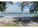 A serene beach scene with a grill and view of houses across the bay, framed by green foliage at 129 Taft Dr # W102, Sarasota, FL 34236