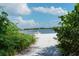 A tranquil beach scene with a boat on the water, framed by lush tropical greenery and a clear sky at 129 Taft Dr # W102, Sarasota, FL 34236
