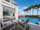 Relaxing outdoor pool area with lounge chairs, swaying palms, and breathtaking ocean views at 1580 Harbor Cay Ln, Longboat Key, FL 34228