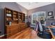 Cozy home office with wood flooring, built-in shelves, and a window with shutters at 2927 Bravura Lake Dr, Sarasota, FL 34240