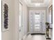 A well-lit foyer with white trim, chandelier, decorative glass front door, artwork, and elegant decor at 3639 Santa Caterina Blvd, Lakewood Ranch, FL 34211