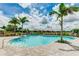 Inviting community pool surrounded by lounge chairs and palm trees under a partly cloudy sky at 3639 Santa Caterina Blvd, Lakewood Ranch, FL 34211