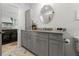 Bathroom with gray vanity, stone countertop, round mirror, and view into a kitchen area at 412 S Casey Key Rd, Nokomis, FL 34275