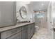 Bright bathroom features gray vanity with stone countertop, round mirror, and a glass enclosed shower with decorative tile at 412 S Casey Key Rd, Nokomis, FL 34275