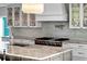 Open-concept kitchen features a stone backsplash, island, stainless steel range, and modern lighting at 412 S Casey Key Rd, Nokomis, FL 34275