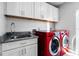 Laundry room features white cabinets, stainless steel sink, and red washer and dryer at 412 S Casey Key Rd, Nokomis, FL 34275