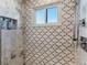 Close up of shower stall with white and brown decorative tile, window, shower head and inset shelving at 412 S Casey Key Rd, Nokomis, FL 34275
