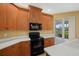 Kitchen with stainless steel appliances, wood cabinets, white countertops, and a sliding glass door to the backyard at 4331 Turnberry Cir, North Port, FL 34288